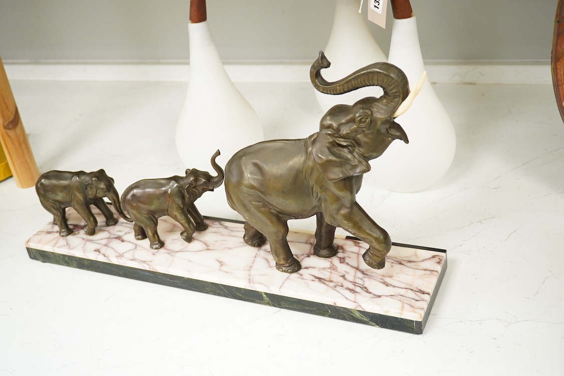 An Art Deco study, three spelter elephants, raised on marble and onyx base, 54cm wide